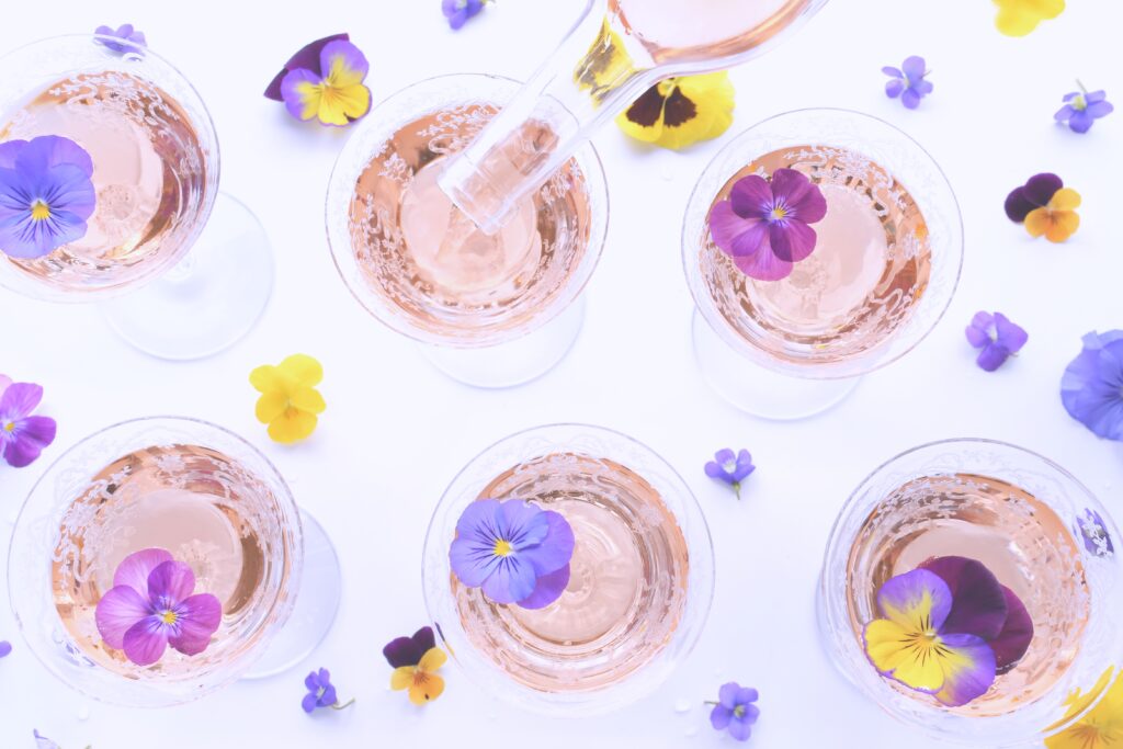 Spring wine cocktails garnished with pansies & violets - flat lay, pastel drinks party, diffused